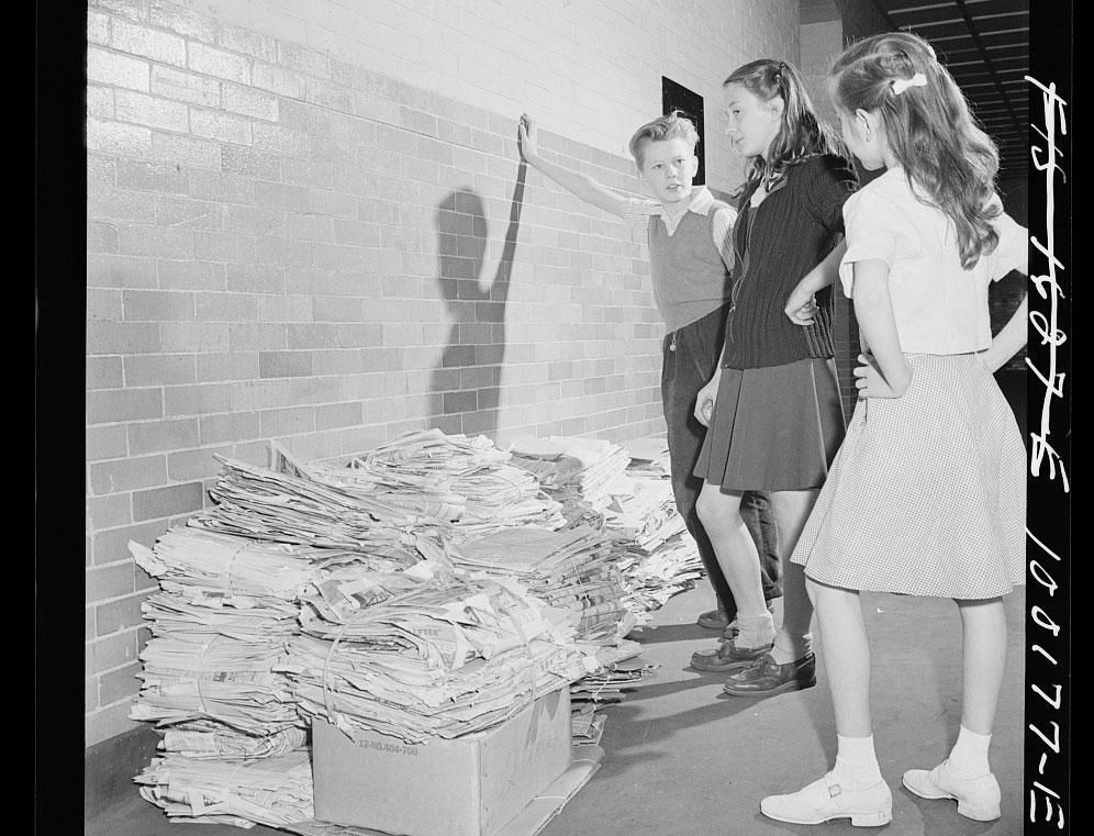 A 1940s photos of students standing over a pile of scrap paper