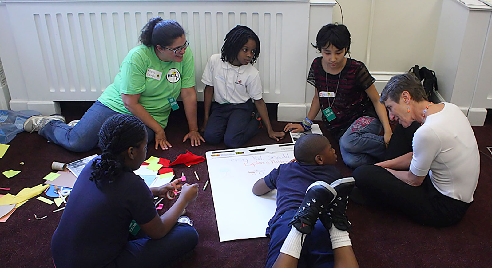 Children and adults sit around a large piece of paper while co-designing the Every Kid in a Park website.