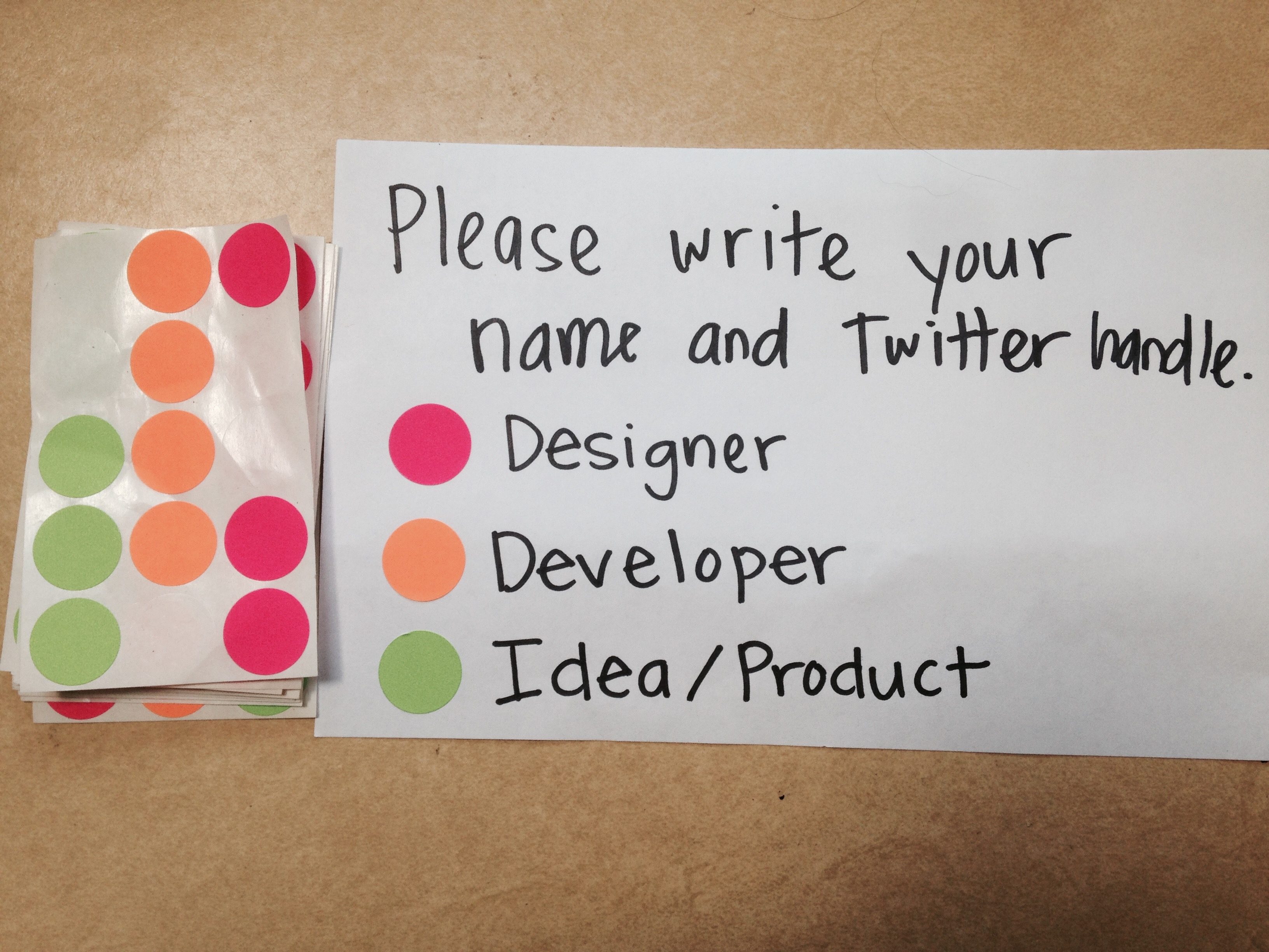 Image: nametag from recent hackathon showing color-coded stickers for devs, designers, and content strategists