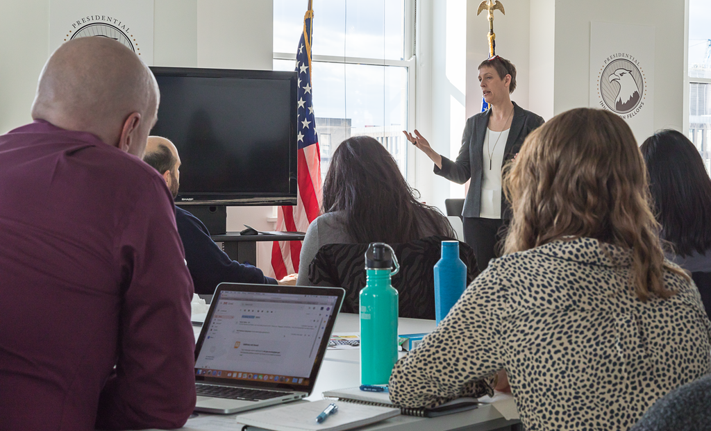 A photo of Acting Executive Director of 18F, Angela
  Colter, addressing the new group of Presidential Innovation Fellows in
  January 2019.